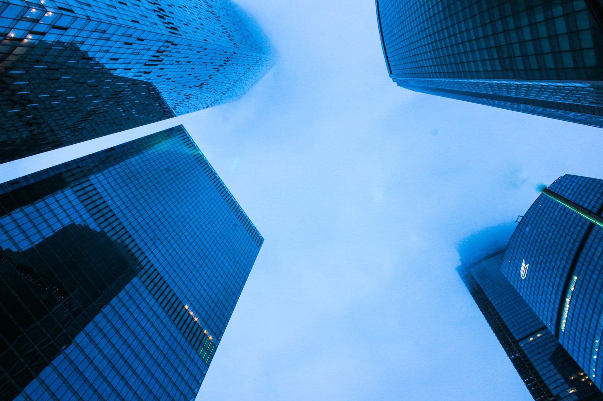 Financial-district towers at dusk, seen from below.
