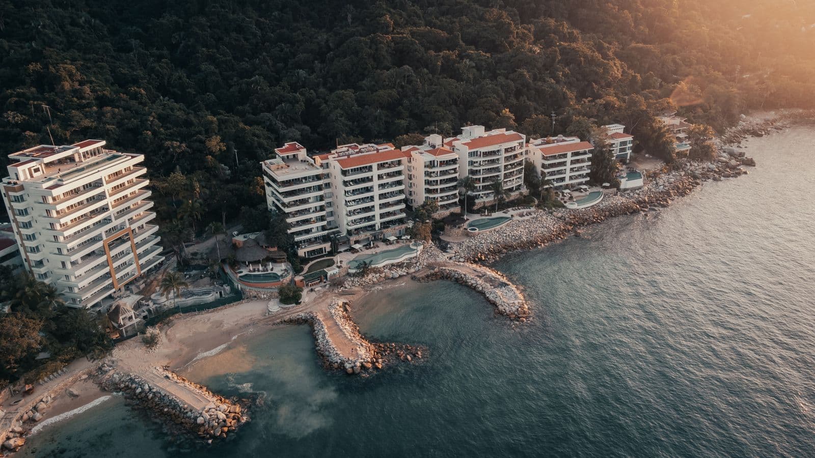 Aerial view of luxury waterfront residences along a turquoise coast.