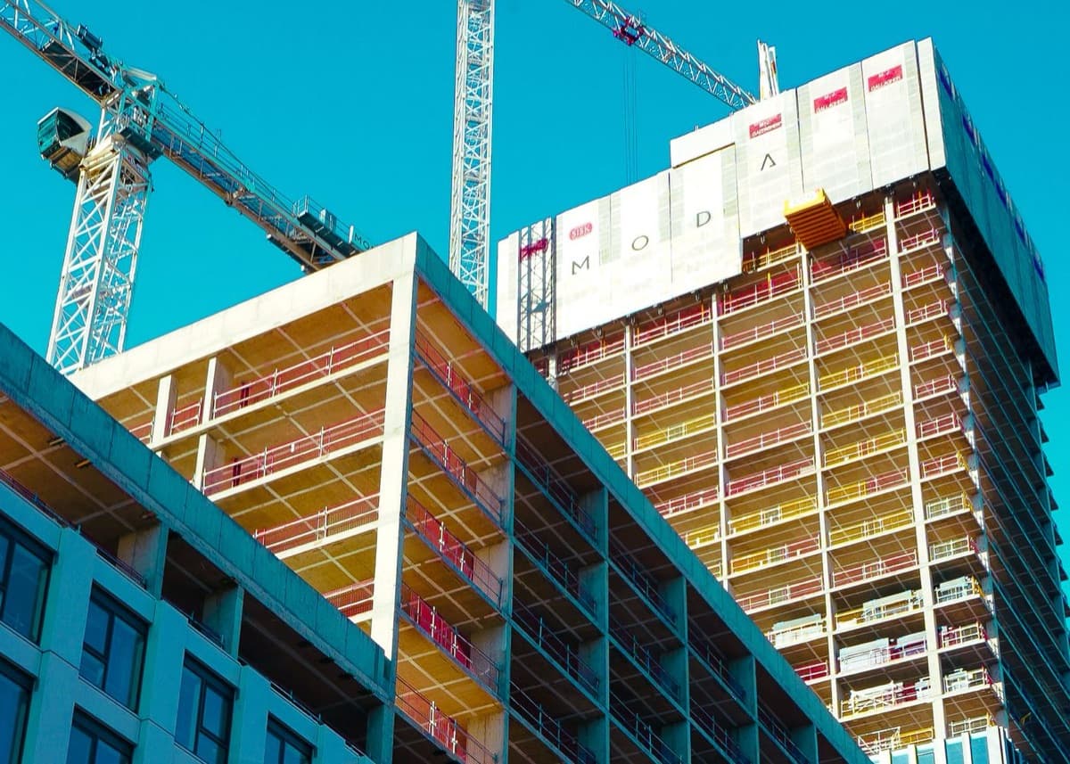 Concrete tower under construction with cranes and formwork