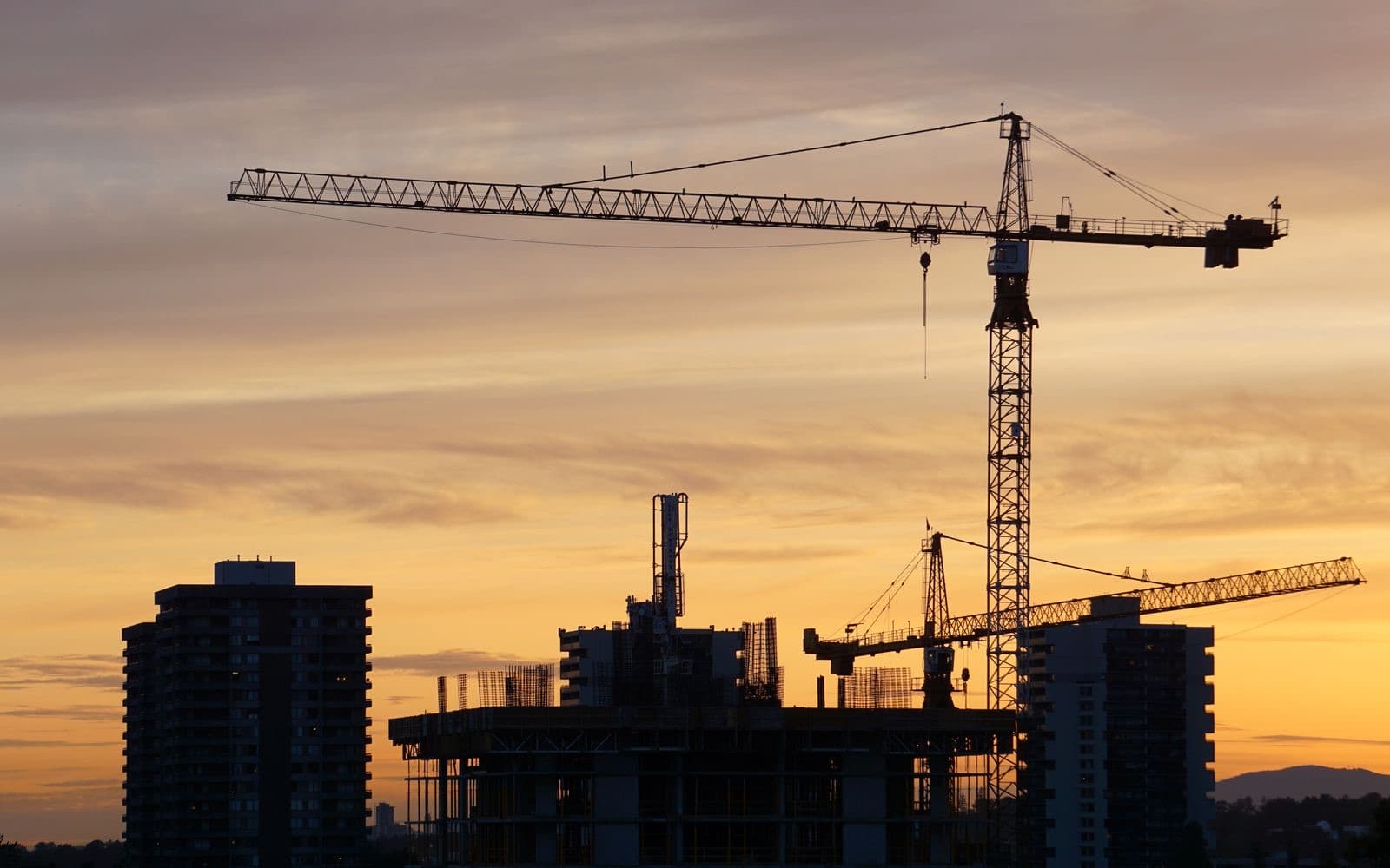 Tower cranes over a building under construction at dusk